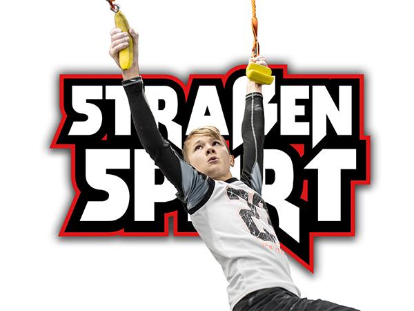 Ein Junge schwingt an einer Kunststoffschaukel, vor einem farbigen Schriftzug &bdquo;STRASSENSPORT&ldquo;.